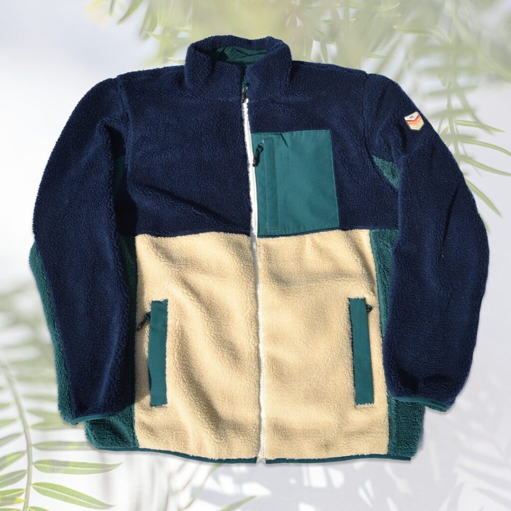 Men's mesh lined sherpa jacket with 3 front pockets in navy and beige colorblocks and turquoise accents.
