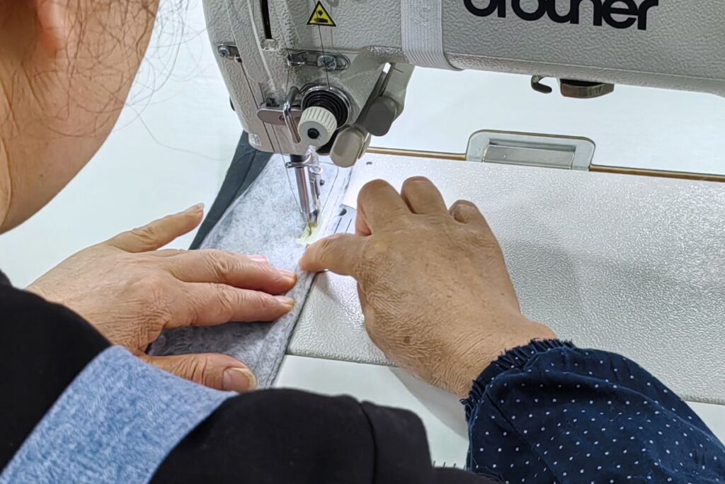 A sewing machine operator precisely stitching a winter jacket component on Itorch Apparel's production line.