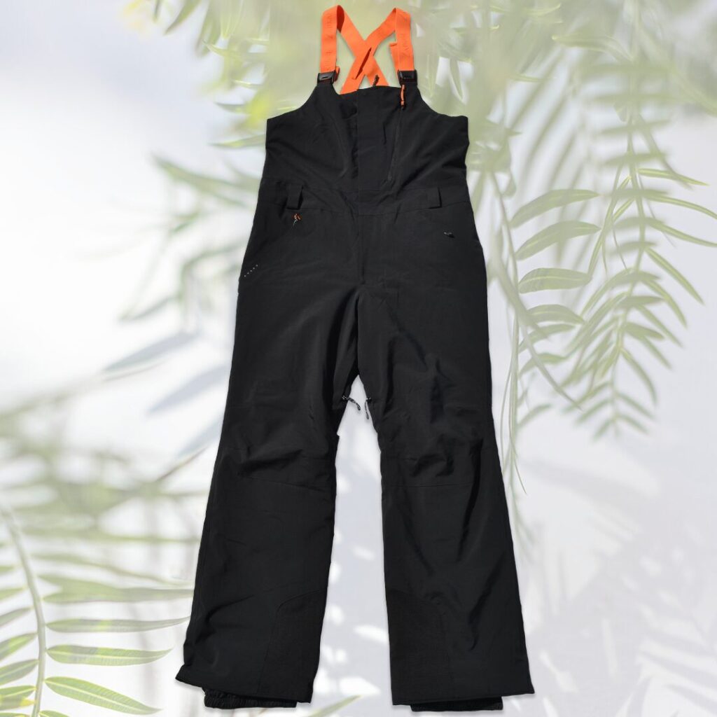 Men's ski bib pants in black with adjustable orange elastic suspenders.